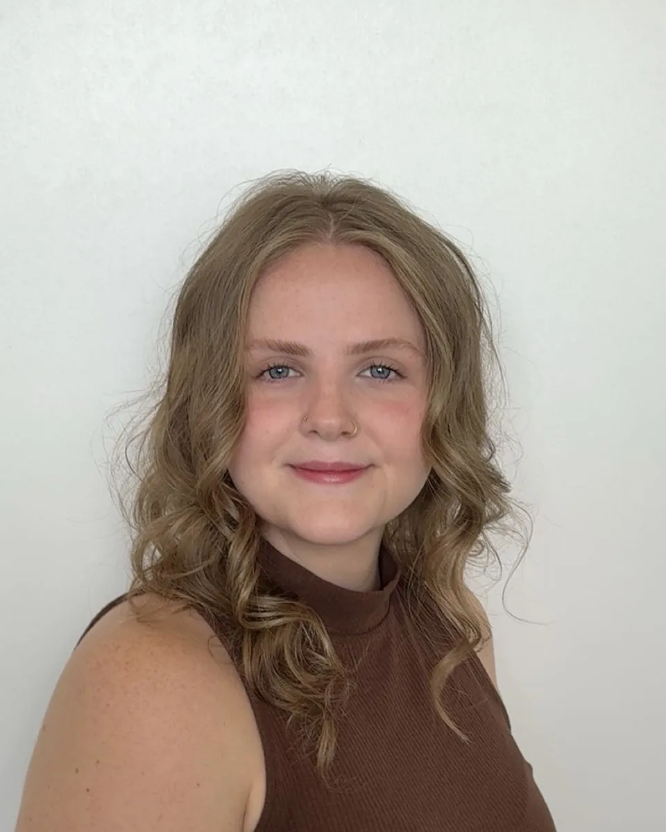 Mackenzie smiling in front of a plain white wall