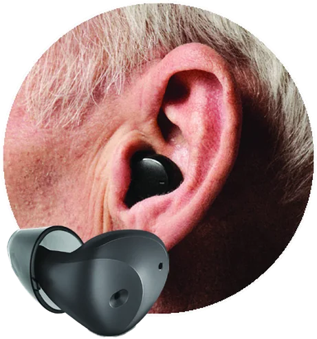An ear wearing a black hearing aid shaped like a wireless earbud, and the hearing aid shown alongside